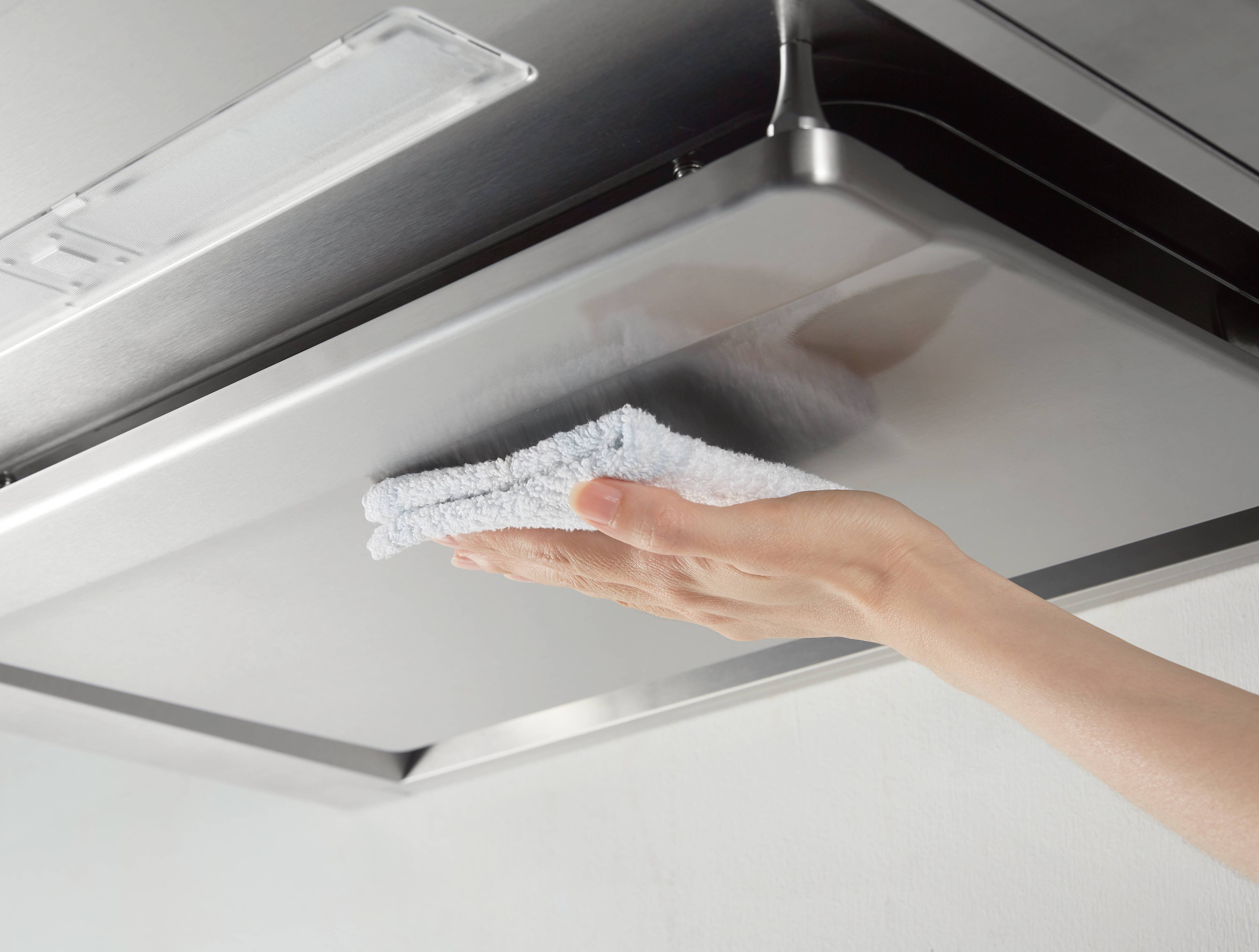 Effortlessly wiping clean the smooth surface of SAKURA M6000 range hood after heavy Asian cooking